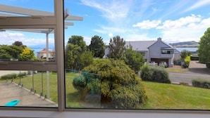 A modern house with a large glass window, a garage, and a view of a green landscape. - Home Away From Home - Taupo (Taupo)