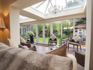 A spacious living room with a high ceiling and skylight, furnished with a sofa, chairs, and a chandelier. - Linwood (Thornton-Cleveleys)