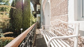 A white bench outside a building with a textured wall and a wooden railing. - Müllers Ferienhaus Salzburgerland (Unken)