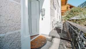 A white door with a mailbox, a wooden bench, and a metal railing on a balcony. - Müllers Ferienhaus Salzburgerland (Unken)