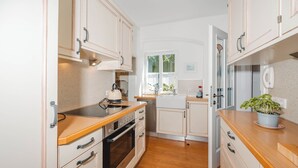 A compact kitchen with wooden countertops, a built-in oven, and white cabinetry. - Müllers Ferienhaus Salzburgerland (Unken)