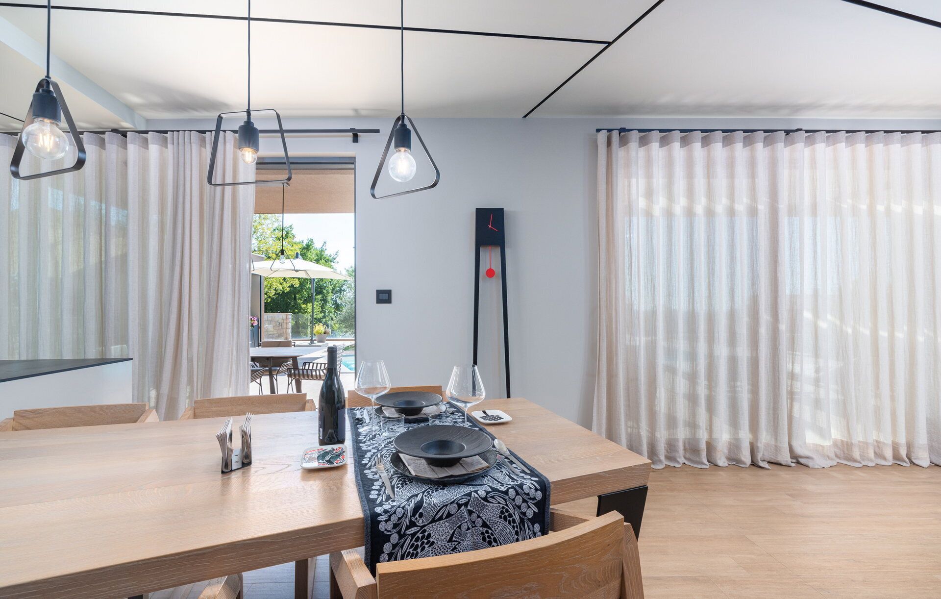 A dining area with a wooden table, chairs, and hanging pendant lights.