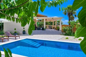 A swimming pool with steps leading to a covered patio area, surrounded by potted plants and outdoor furniture. - Villa Valloverde with Pool (Dobrinj)