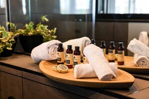 A bathroom counter with toiletries, towels, and a plant.