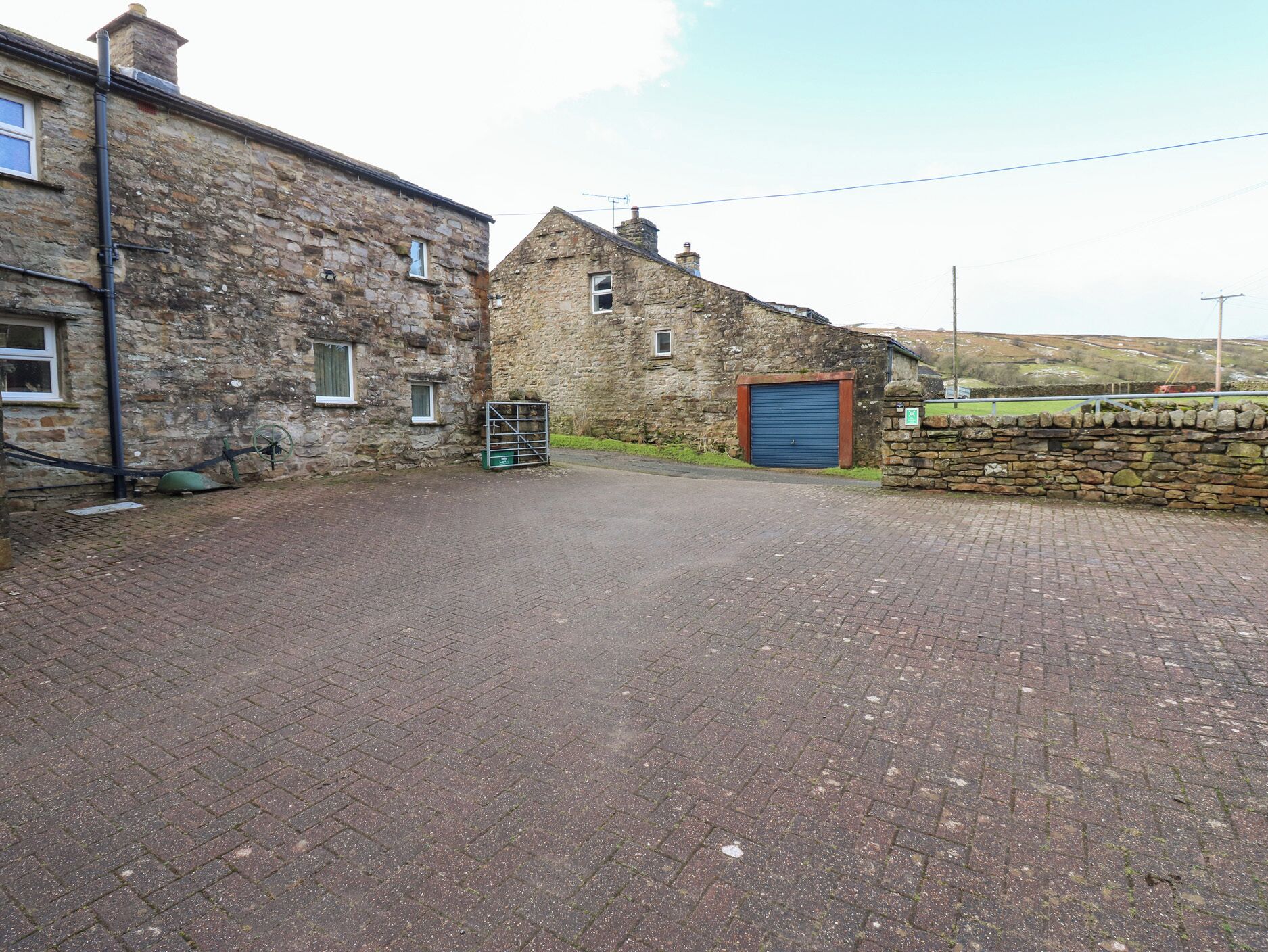 A paved driveway leading to a stone building with a blue garage door.