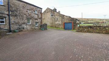 A paved driveway leading to a stone building with a blue garage door.