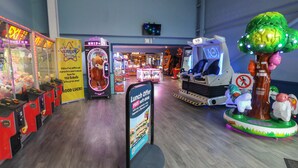 A VR experience area with a tree-shaped VR station, claw machines, and a sign offering a lunch discount. - Shipwreck Chalet (Kidwelly)