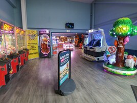 Zona de experiencias de realidad virtual con una estación de realidad virtual con forma de árbol, máquinas de garrapatas y un cartel que ofrece descuento para el almuerzo.