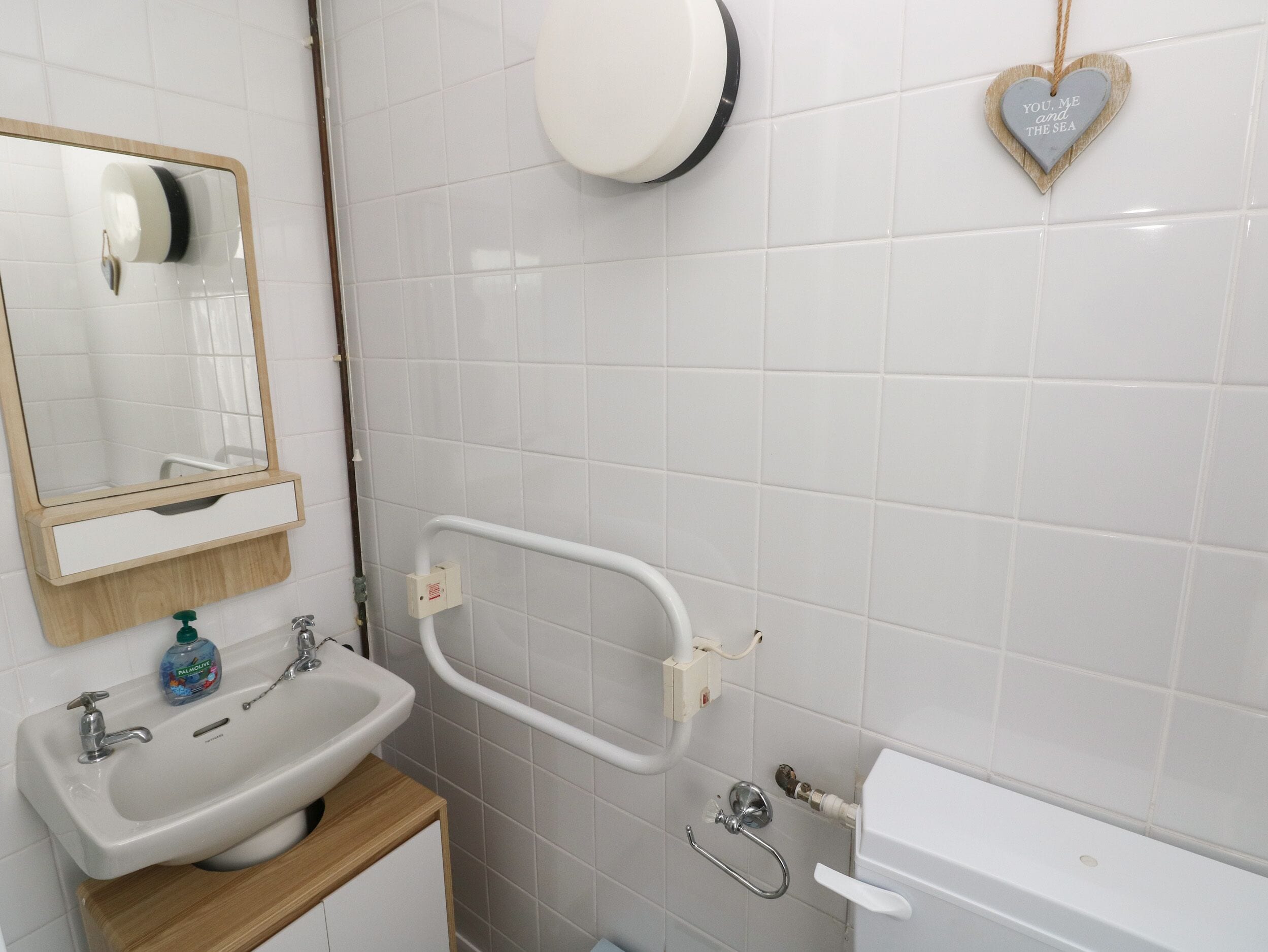 Ein Badezimmer mit einem weißen Waschbecken, Spiegel und WC.