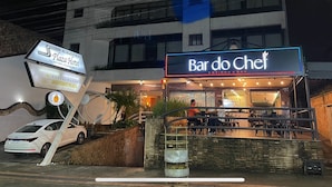 Un restaurant appelé Bar do Chef, avec des tables en plein air, et une enseigne indiquant l’hôtel Alagoinhas Plaza en arrière-plan.