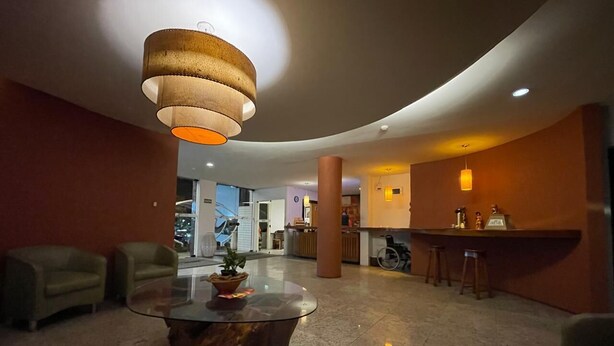 Un hall d’entrée avec une table ronde en verre, deux canapés, un luminaire suspendu et un coin bar.