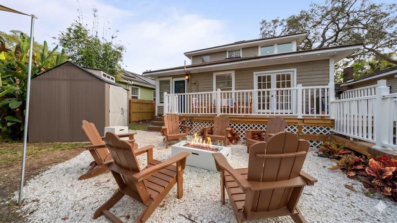 A backyard with outdoor seating, a fire pit, and a house with a deck.
