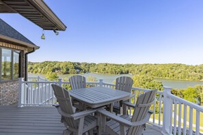 A deck with a table and chairs overlooking a lake and forest.
