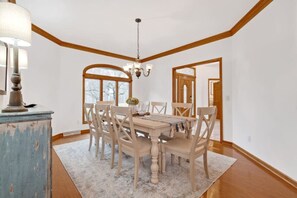 A dining area with a wooden table and chairs, a chandelier, and a blue cabinet.