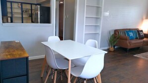 Un comedor con una mesa y sillas blancas, un sofá de cuero marrón y una estantería.
