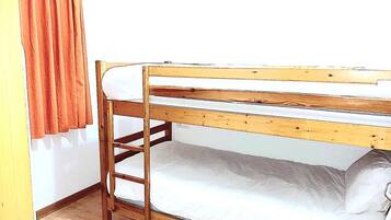A bunk bed with a ladder, white bedding, and a wooden frame.