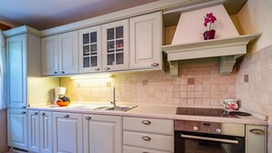 A kitchen with white cabinets, a stainless steel sink, a Bosch oven, and a small red vase with flowers on the countertop.