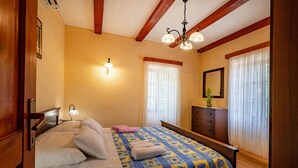 A bedroom with a bed, bedside lamps, a dresser, a mirror, and a window with curtains.