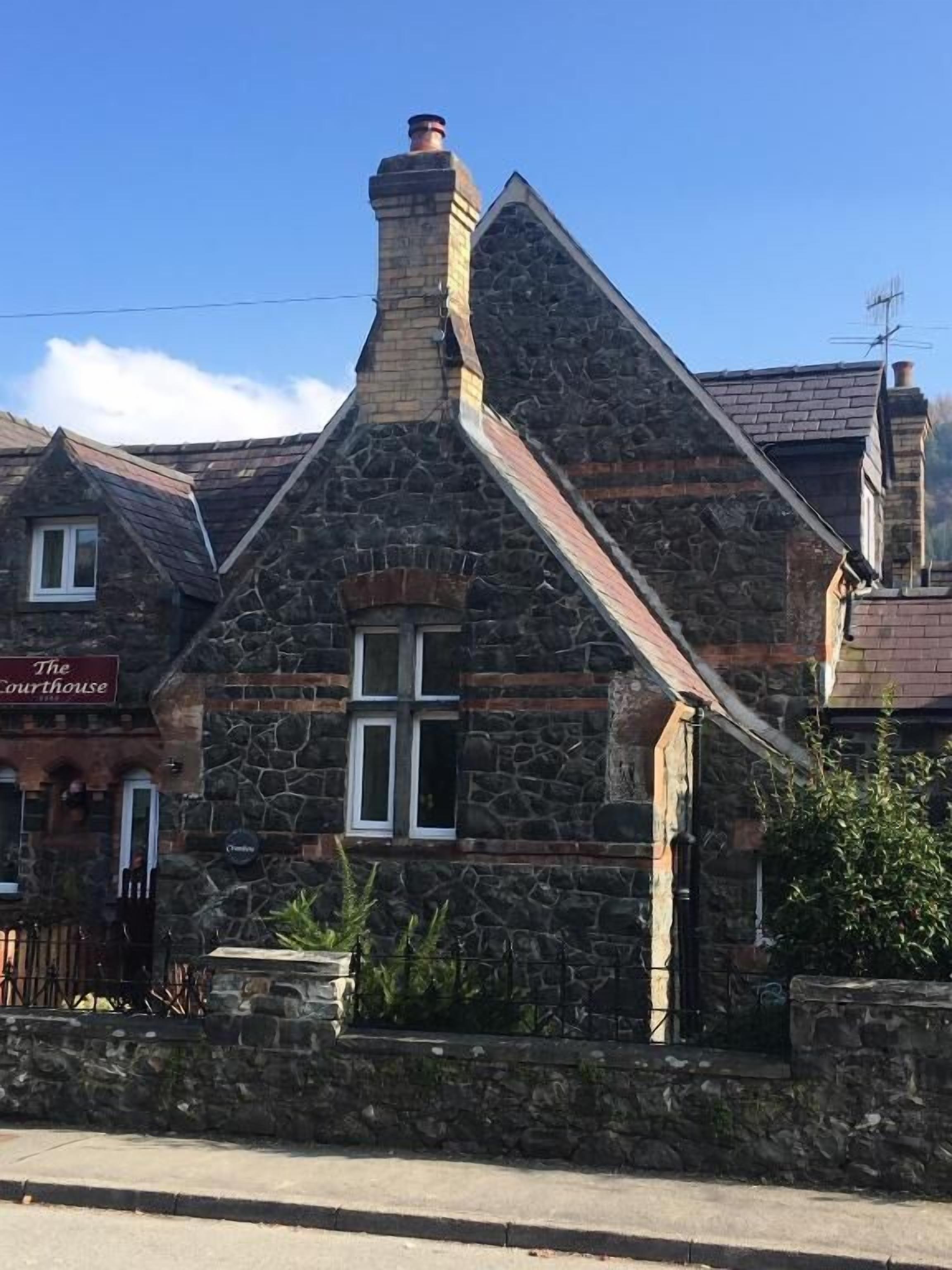 Un bâtiment en pierre avec un toit à deux versants et une cheminée.