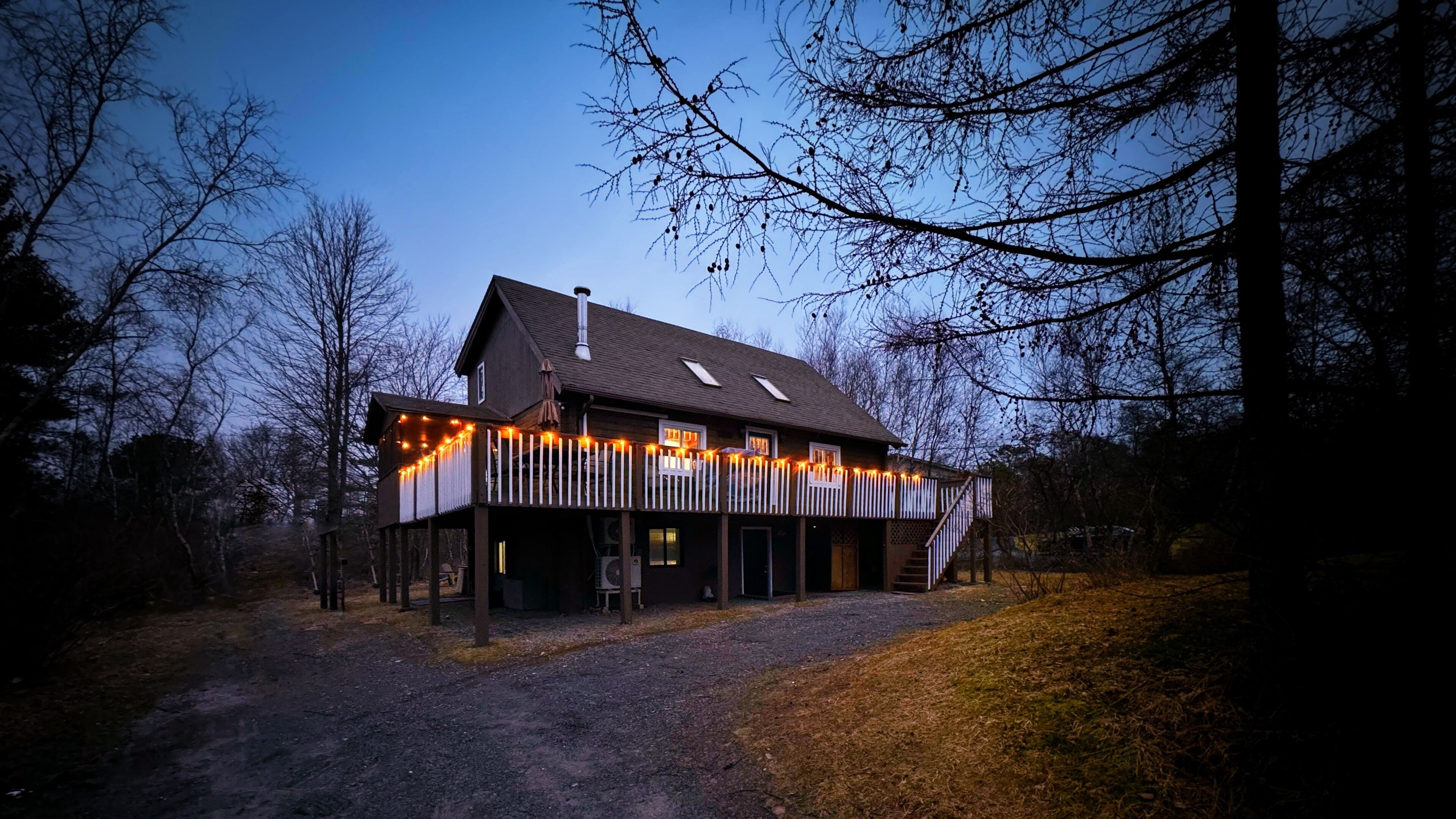 A two-story house with a covered porch, a front deck, and a driveway.