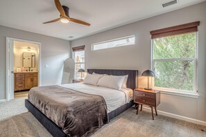 Ein Schlafzimmer mit Bett, Nachttisch, Deckenventilator und Fenstern.