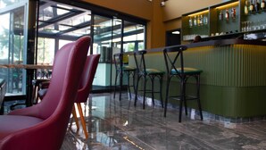 Un área de bar moderna con un separador de vidrio, sillas rojas y una barra verde.