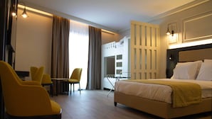 Habitación de hotel con cama, escritorio, dos sillas y armario.