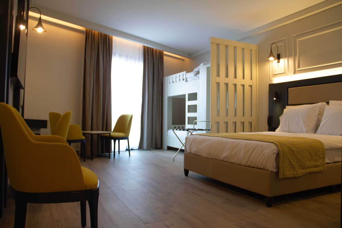 A hotel room with a bed, a desk, two chairs, and a wardrobe.