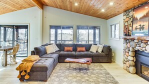 Ein modernes Wohnzimmer mit einer Eckcouch, einer Holzbalkendecke und einem Steinkamin.