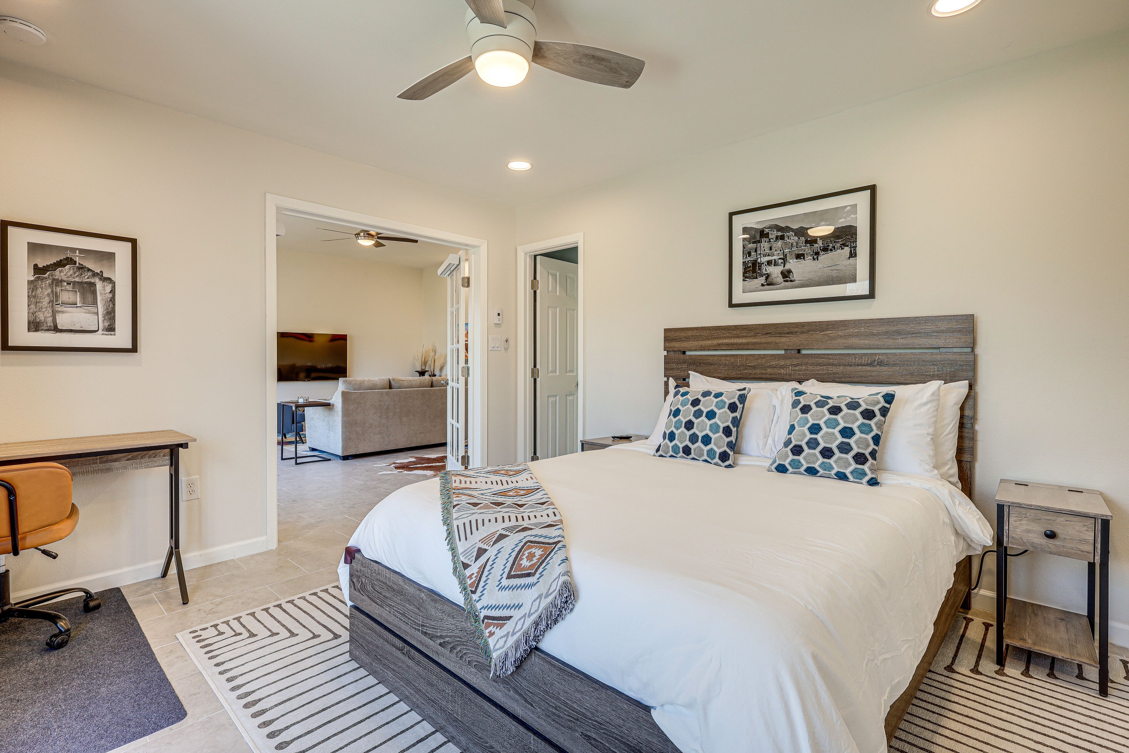 A bedroom with a bed, a desk, a chair, a nightstand, and a ceiling fan.