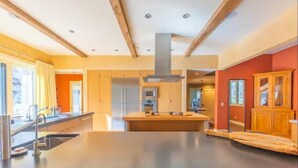 Une cuisine moderne dotée d’un îlot central, d’appareils électroménagers en acier inoxydable et de meubles de rangement en bois.