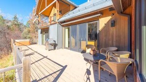 Une cabane en bois dotée d’une terrasse, d’un espace salon extérieur et d’un barbecue.