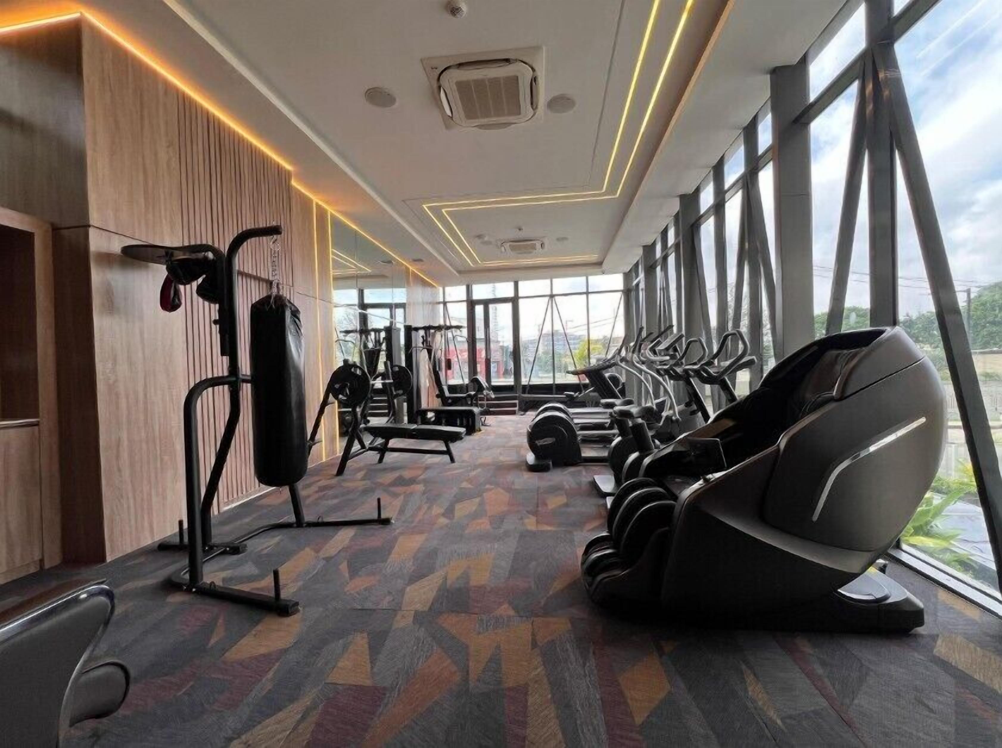 A gym with exercise equipment, large windows, and a patterned floor.
