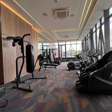 Un gimnasio con equipamiento de ejercicio, ventanas amplias y piso con diseño.