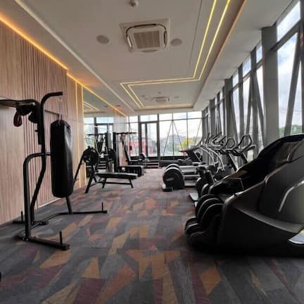 A gym with exercise equipment, large windows, and a patterned floor.