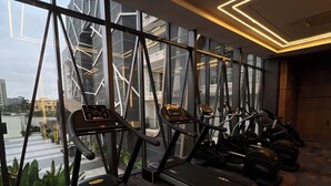 A gym with treadmills aligned against a wall with large windows, offering views of a cityscape. - The Delborough Lagos (Lagos)