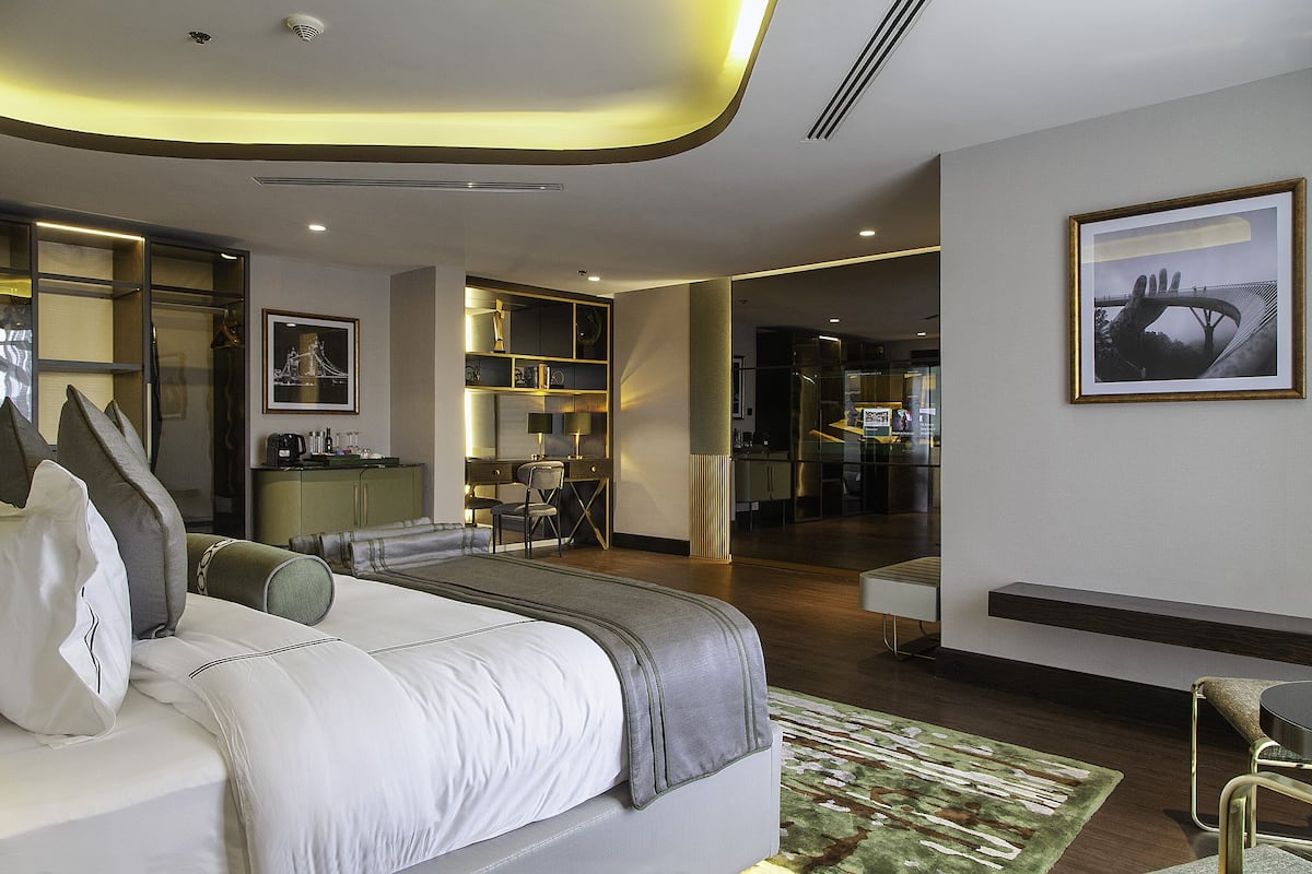 A modern hotel room with a large bed, a desk, and a seating area.