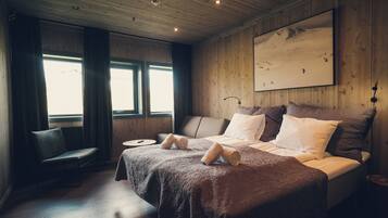 A wooden-paneled bedroom with a bed, a chair, and a painting on the wall.