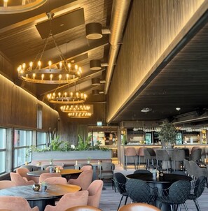 A modern interior with a bar area, seating arrangements, and a chandelier.