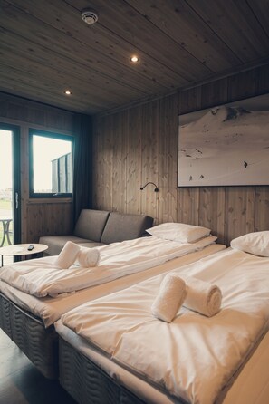 A room with two beds, a sofa, a small table, and a window.