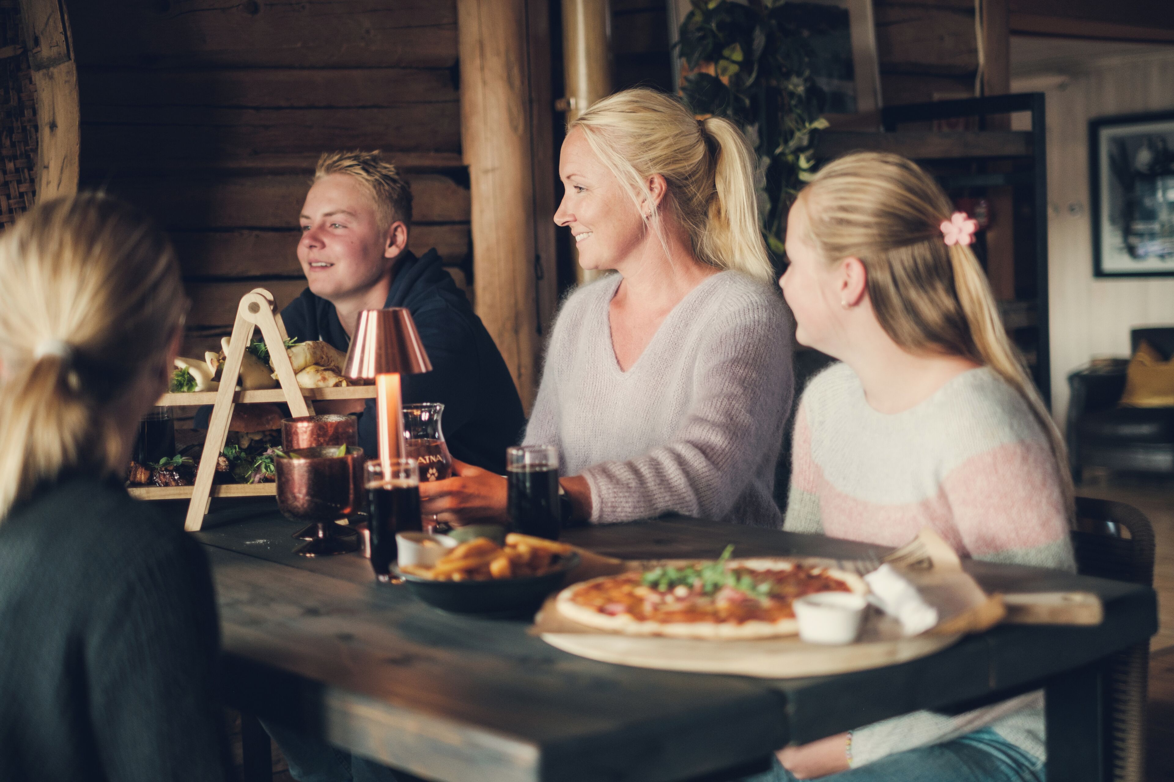 Et træinteriør med et bord dækket til et måltid, inklusive pizza og drikkevarer.