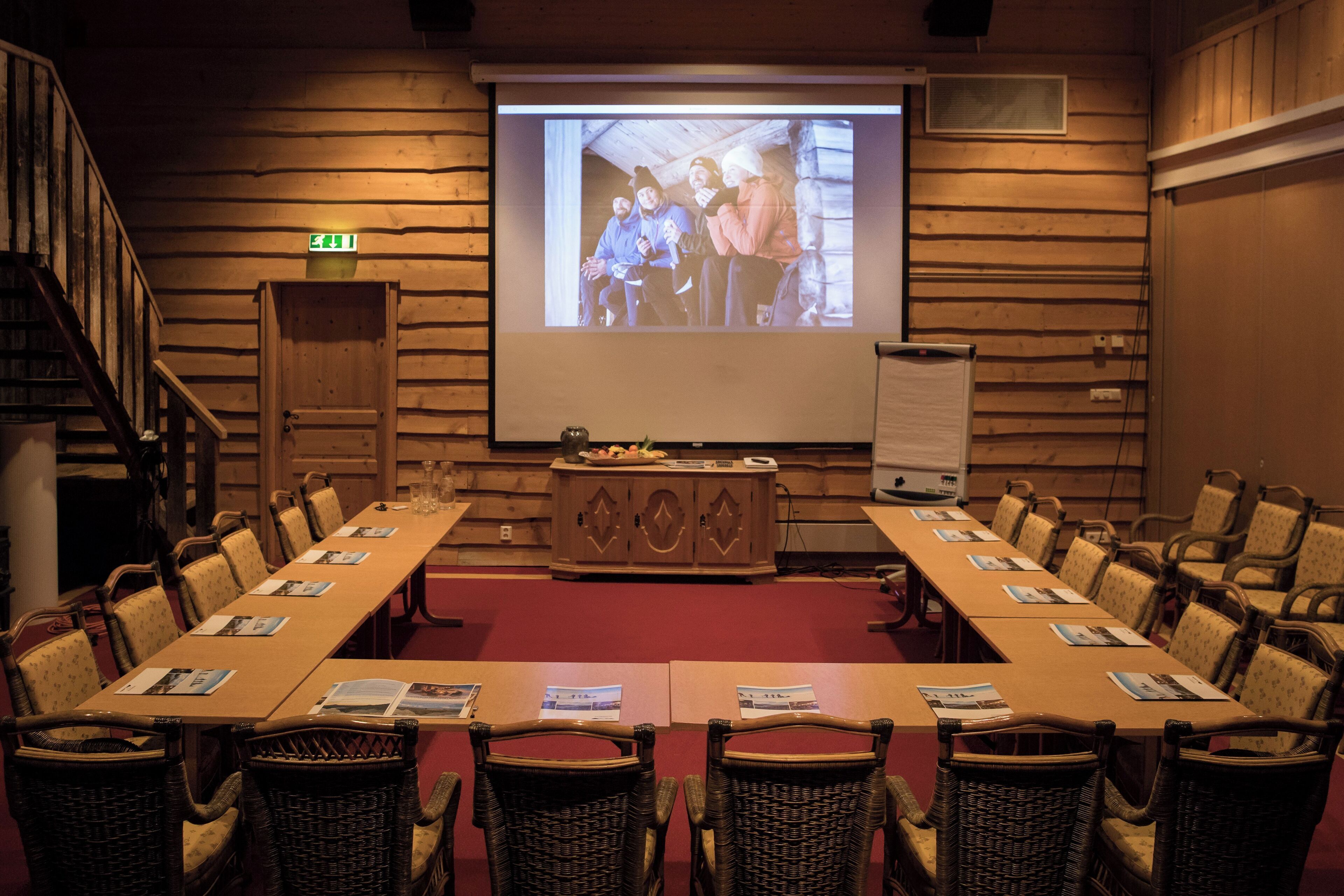 A conference room with a long table, chairs, a podium, and a projection screen.