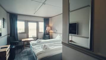 A hotel room with two beds, a desk, a chair, a TV, and a window with curtains.