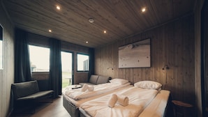 Een kamer met twee bedden, een bank, een kleine tafel en een raam met gordijnen.
