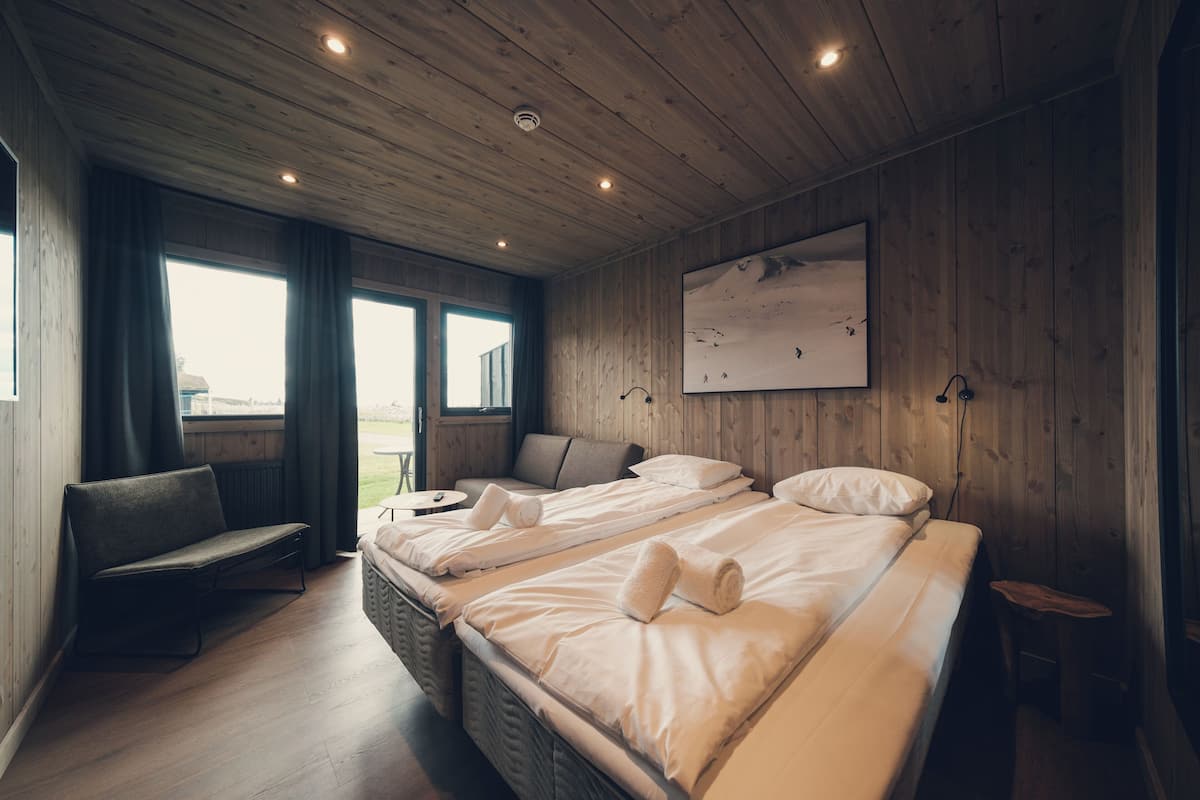 Una habitación con dos camas, un sofá, una mesita y una ventana con cortinas.
