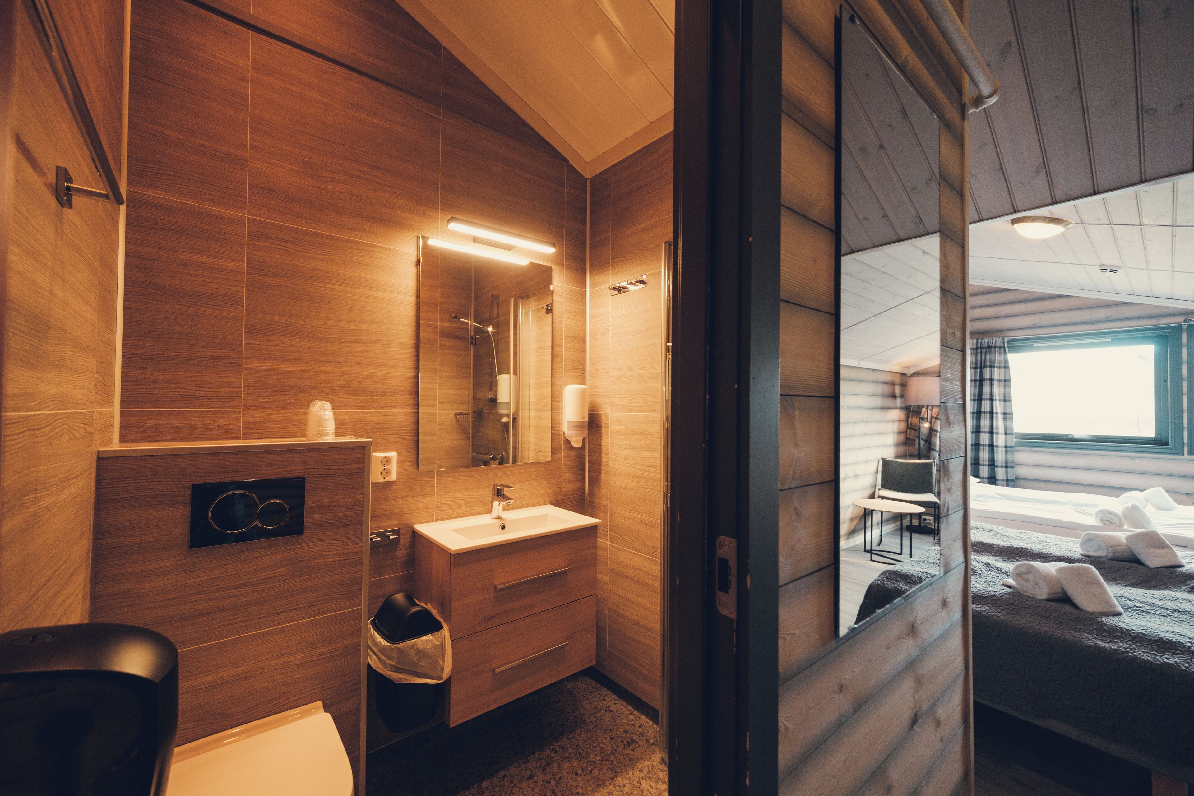 A modern bathroom with wooden walls, a sink, and a mirror.