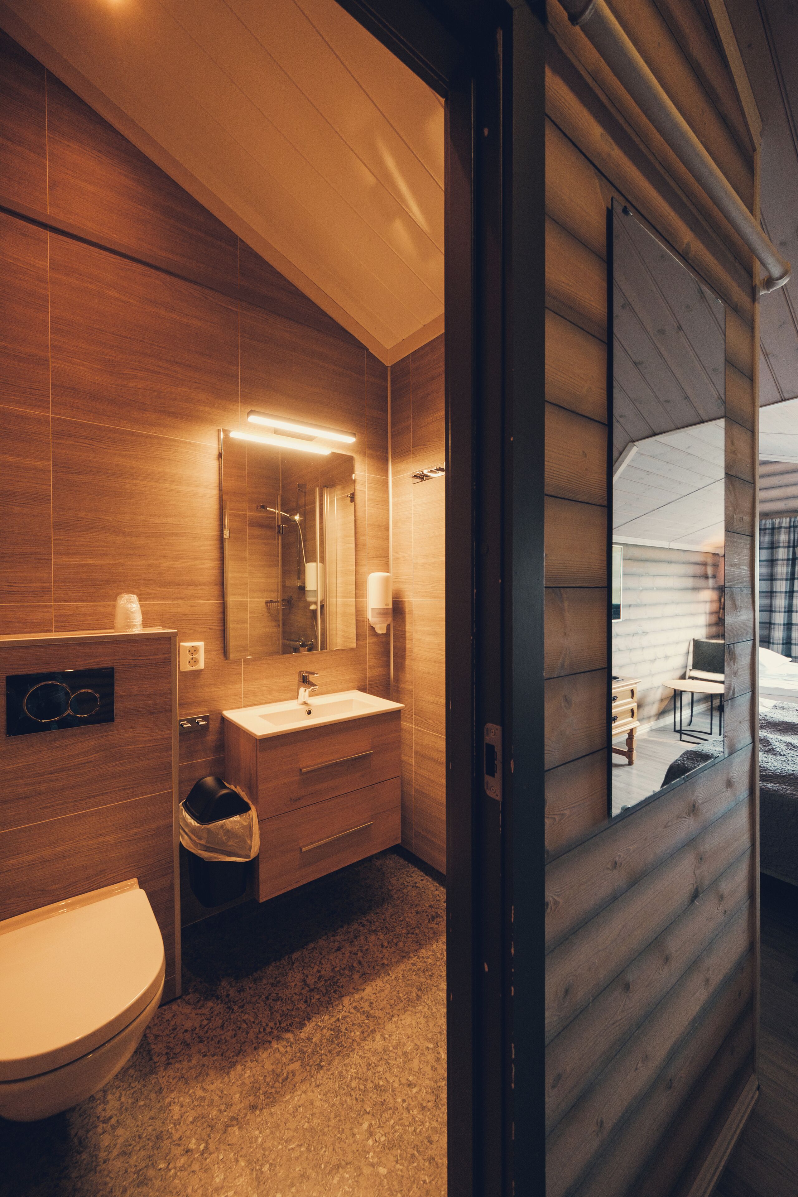 A modern bathroom with wooden paneling, a white sink, and a large mirror.