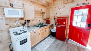 A wooden cabin-style kitchen with a white stove, a red refrigerator, and wooden cabinets. - Cozy tiny cabin in Petros -Windrock (Oliver Springs)
