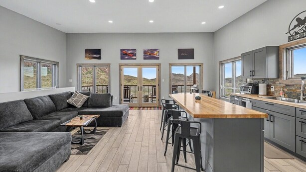 Una cocina moderna con una isla central, taburetes de bar y una zona de comedor con sofá y mesa de centro.