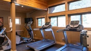 Un gimnasio con cintas de correr, una bicicleta estática y una máquina de remo.